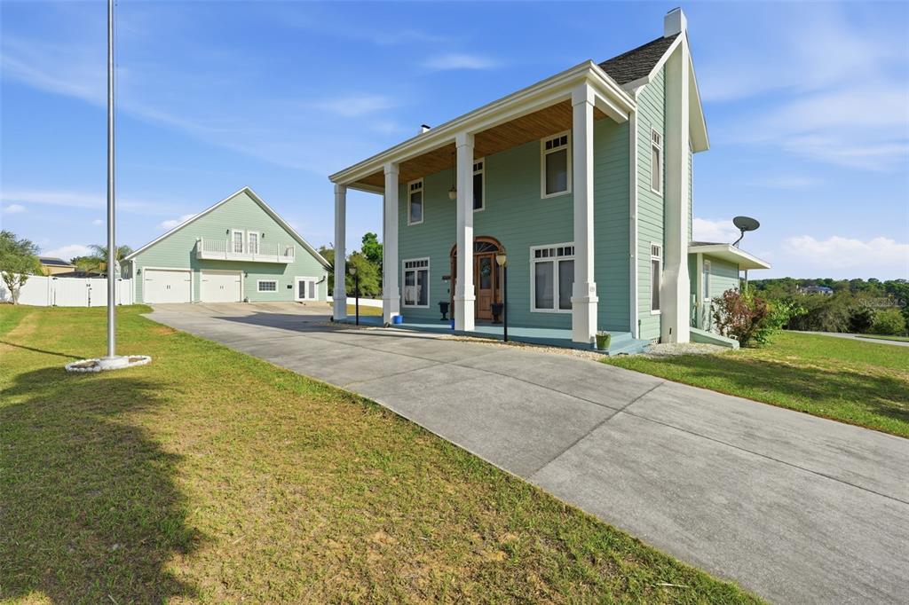 A two-story light green house with a large front porch and a detached garage — 835 BUTCH CASSIDY LANE, EUSTIS, FL