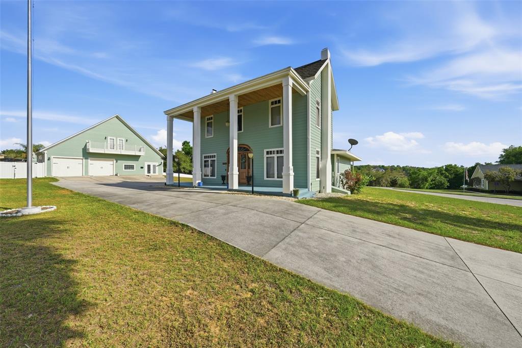 A two-story light green house with a large front porch and a detached garage — 835 BUTCH CASSIDY LANE, EUSTIS, FL
