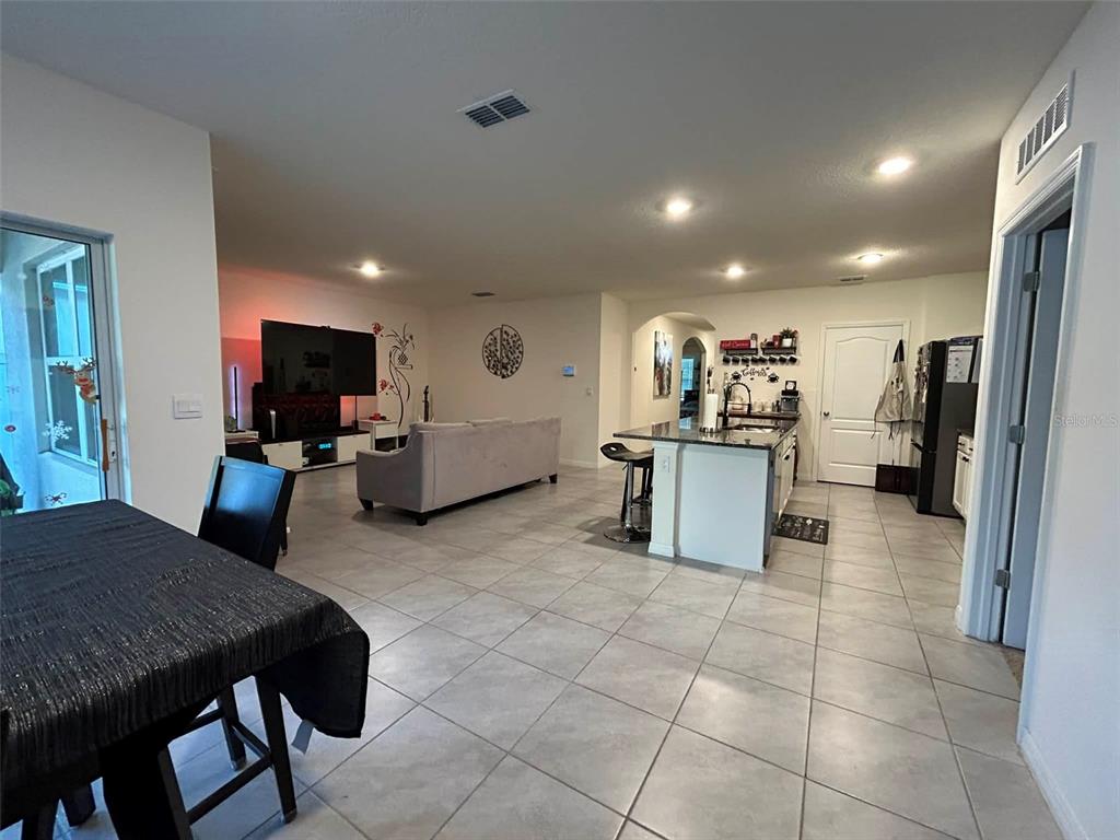 An open-concept living room and kitchen feature tile flooring, a gray sofa, and a kitchen island — 2612 HARMONIA HAMMOCK ROAD, HARMONY, FL