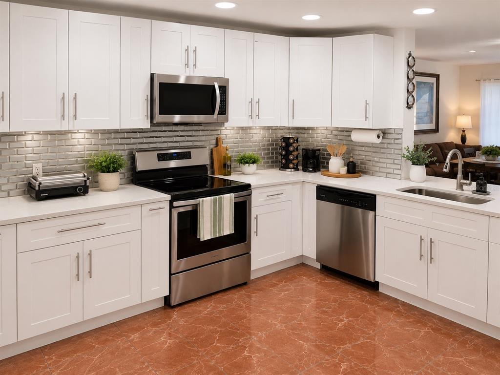 A kitchen with white cabinets, stainless steel appliances, gray subway tile backsplash, and reddish-brown flooring — 499 CHICAGO WOODS CIRCLE, ORLANDO, FL