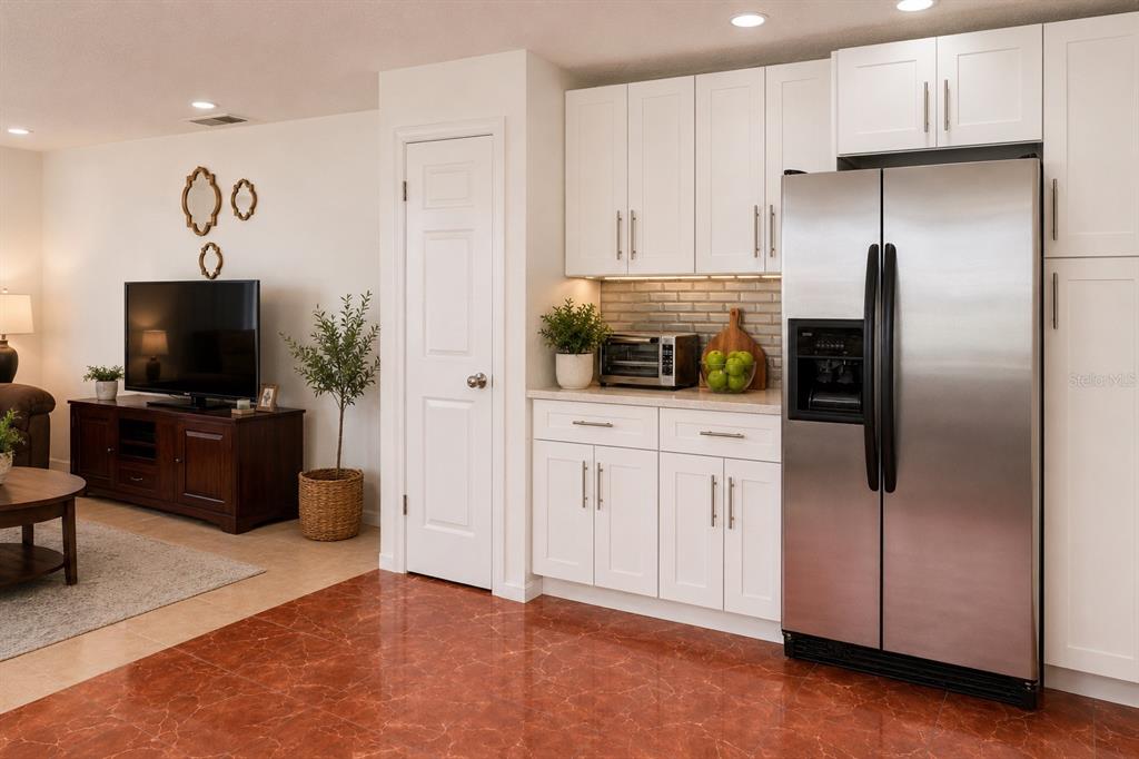 A kitchen with white cabinets, stainless steel refrigerator, and reddish-brown tiled flooring — 499 CHICAGO WOODS CIRCLE, ORLANDO, FL