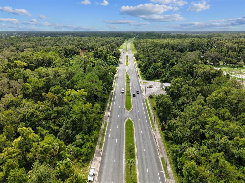 An aerial view shows a divided highway running through a dense, green forest — 000 S MAIN STREET, CHIEFLAND, FL