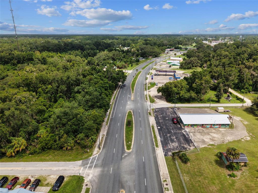 An aerial view shows a divided highway running through a wooded area with commercial buildings — 000 S MAIN STREET, CHIEFLAND, FL