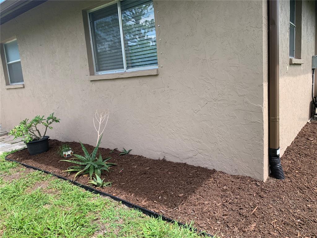 The exterior of a tan stucco house features a window with hurricane shutter anchors — 18094 ACKERMAN AVENUE, PORT CHARLOTTE, FL