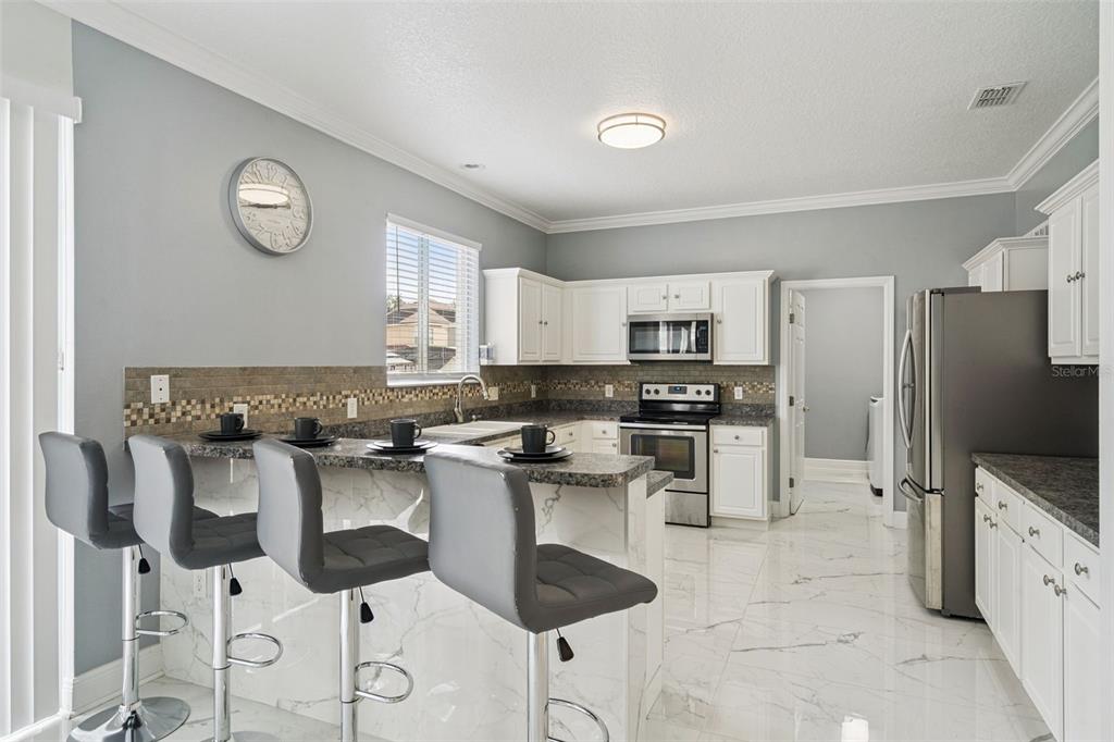A dining room with a glass table, gray chairs, and a diagonal painted wall accent — 233 ROSSELLI BOULEVARD, DAVENPORT, FL