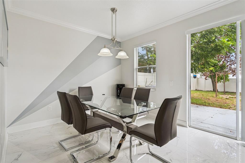 A kitchen features white cabinets, granite countertops, a marble-patterned island with bar stools, and tile flooring — 233 ROSSELLI BOULEVARD, DAVENPORT, FL