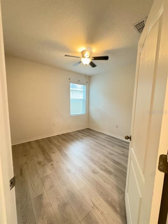 A bedroom features a bed, light wood-look flooring, two white doors, and a wall-mounted desk — 329 WINGED ELM DRIVE, DEBARY, FL