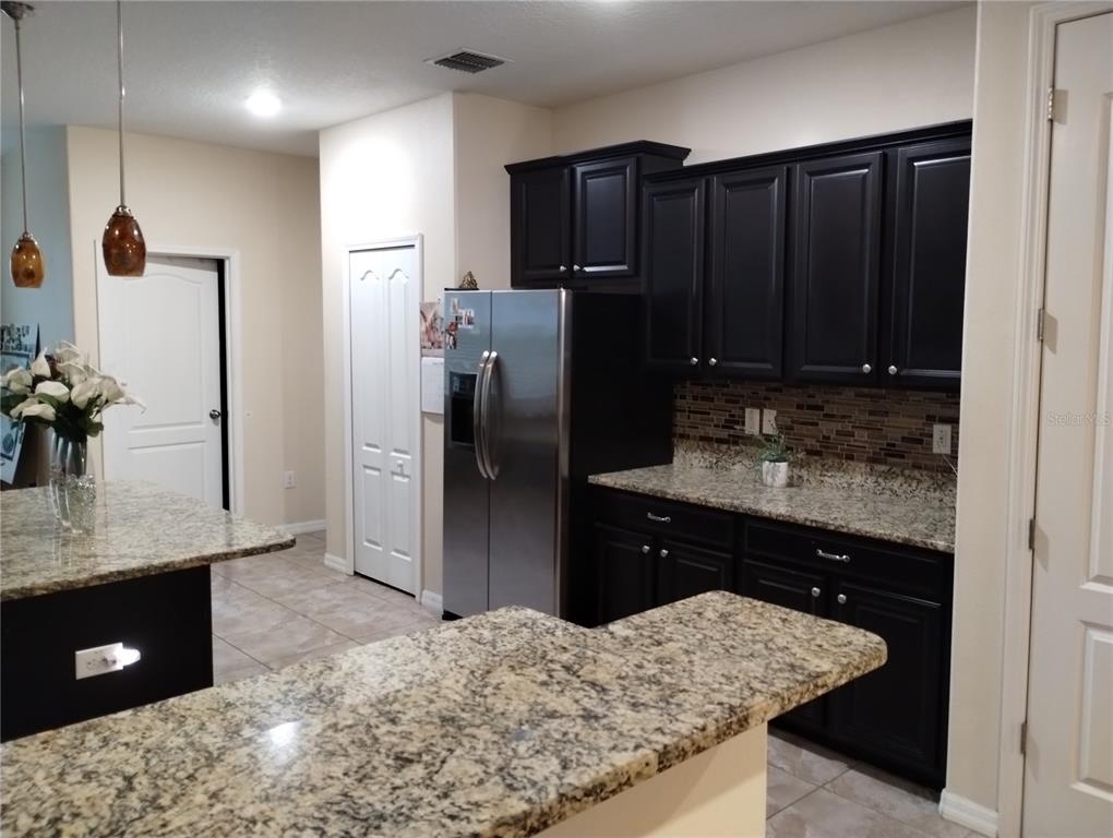 A kitchen features dark cabinets, granite countertops, stainless steel appliances, and a breakfast bar — 12722 DRAKEFIELD DRIVE, SPRING HILL, FL