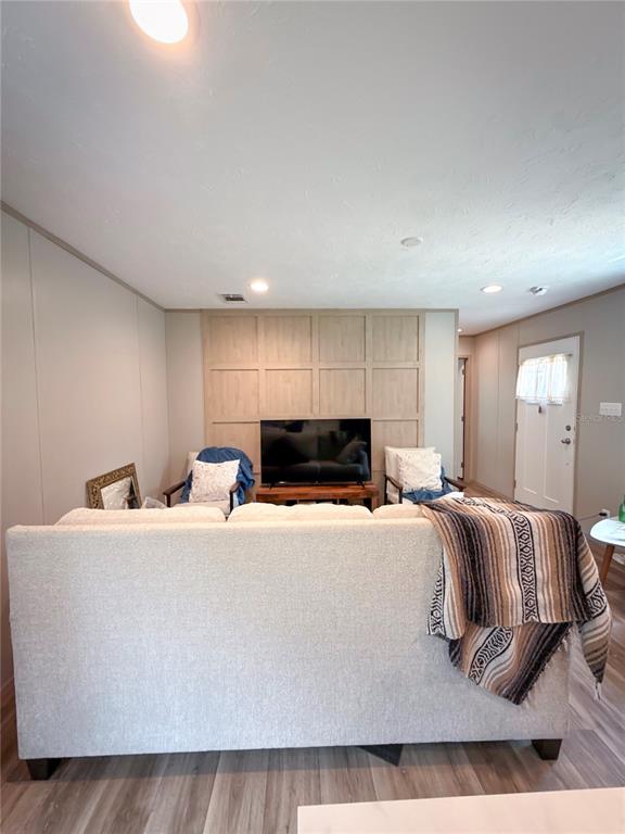 A living room features a light-colored sofa, a television on a wooden stand, and wood-paneled walls — 17690 SE 35TH TERRACE, INGLIS, FL