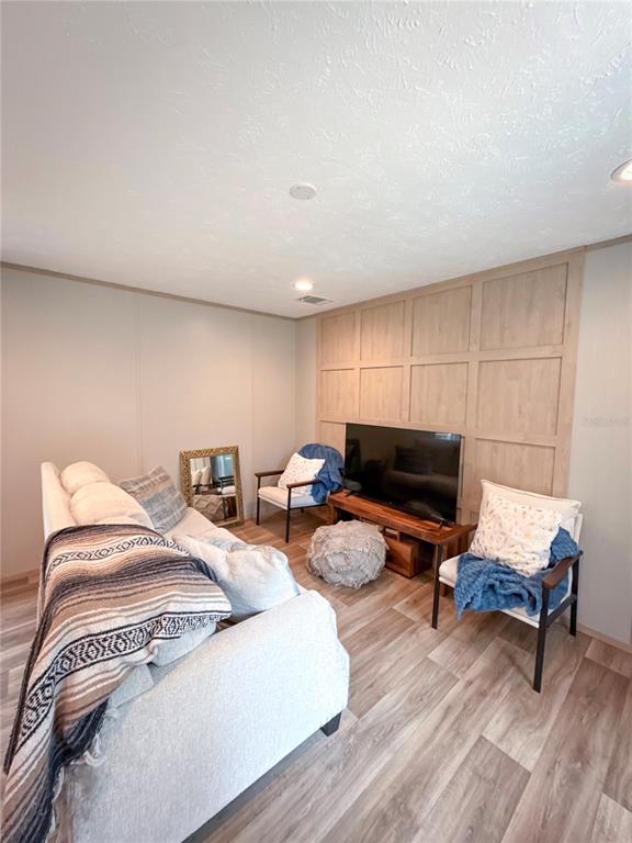 A living room features light wood flooring, a paneled accent wall, and neutral-toned furniture — 17690 SE 35TH TERRACE, INGLIS, FL