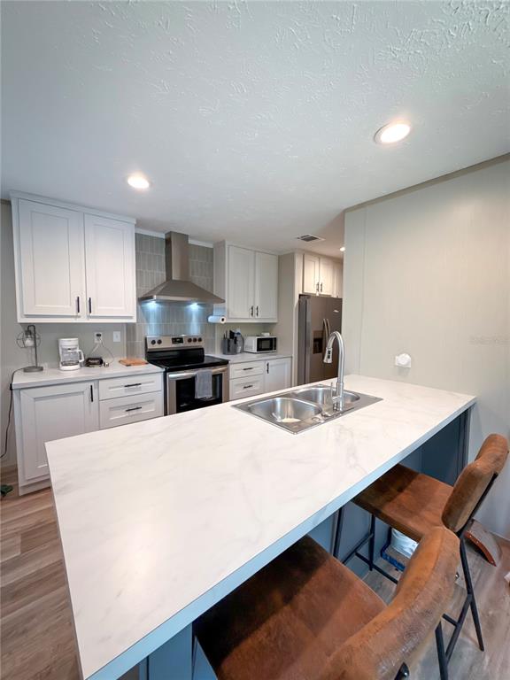A kitchen features white cabinets, a marble-look island with a sink, and stainless steel appliances — 17690 SE 35TH TERRACE, INGLIS, FL