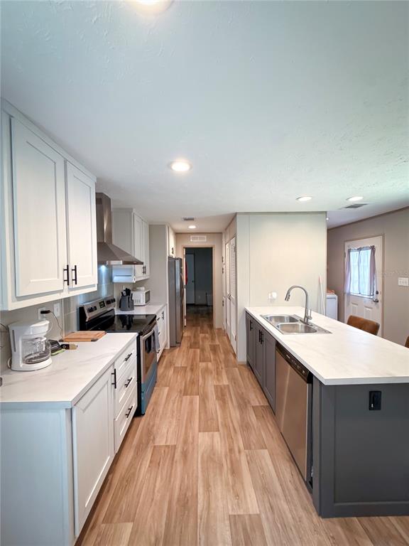 A kitchen features white upper cabinets, a central island with a sink, and wood-look flooring — 17690 SE 35TH TERRACE, INGLIS, FL