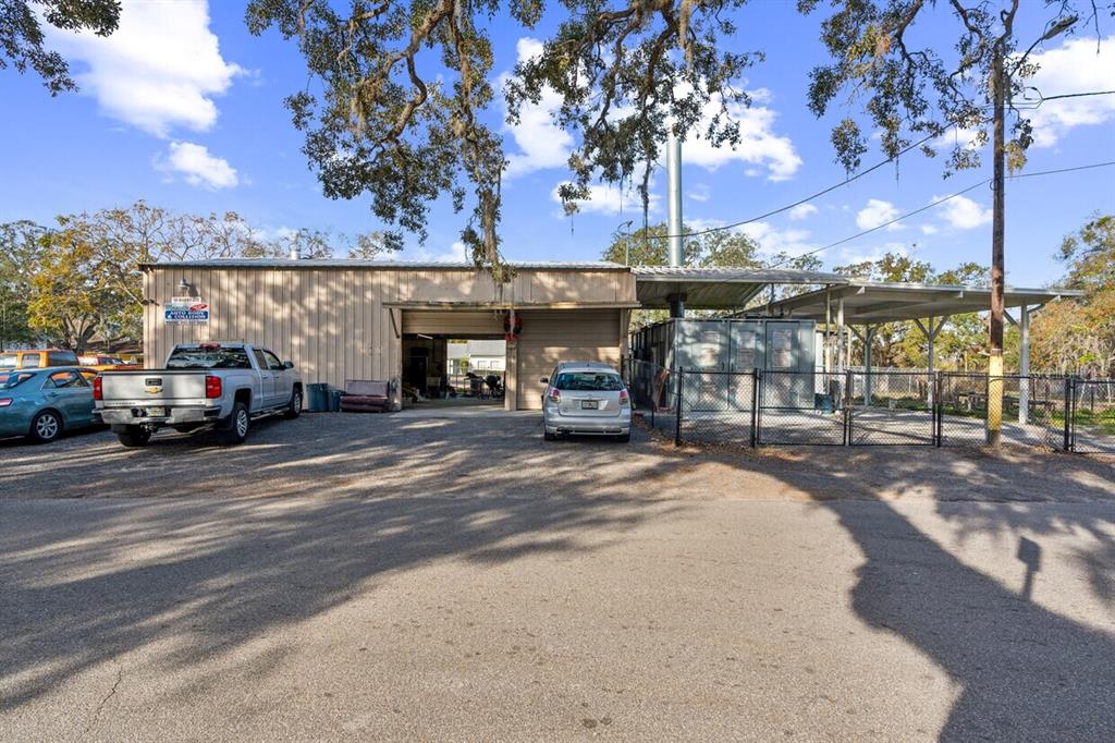 An exterior view of a metal-sided auto body shop with a gravel parking lot — 10 BARRY AVENUE, MASCOTTE, FL