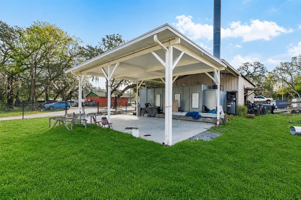 An aerial view shows several small buildings, a parking area, and a lake surrounded by trees — 10 BARRY AVENUE, MASCOTTE, FL