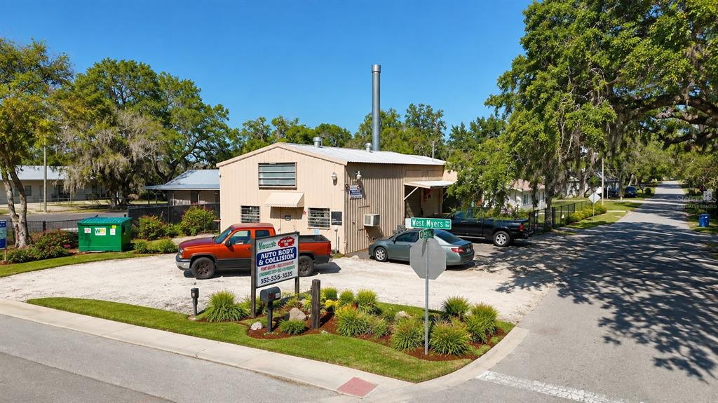 An industrial auto repair garage features a concrete floor, exposed rafters, and a covered car — 10 BARRY AVENUE, MASCOTTE, FL