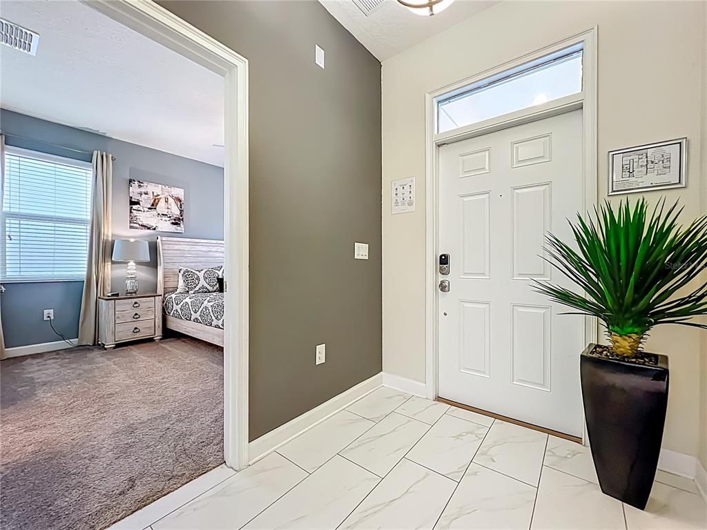 An entryway with white tile floors leads to a bedroom with gray walls and carpet — 9018 STINGER DRIVE, DAVENPORT, FL