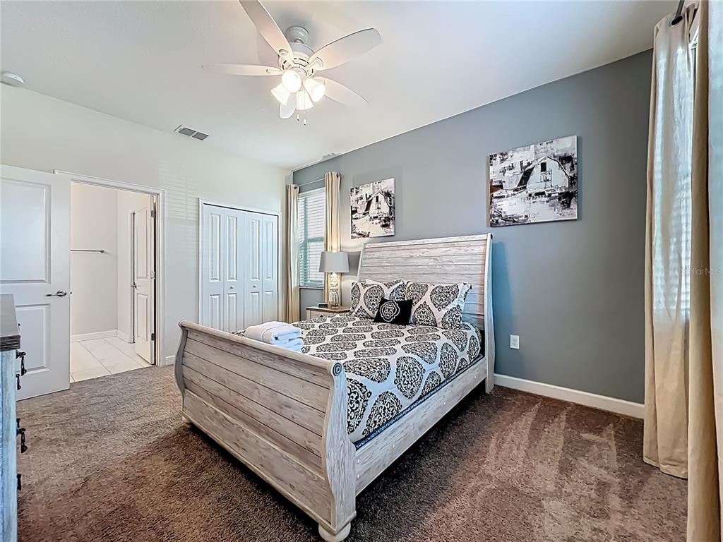A bedroom features a light wood sleigh bed, gray accent wall, and an attached bathroom — 9018 STINGER DRIVE, DAVENPORT, FL