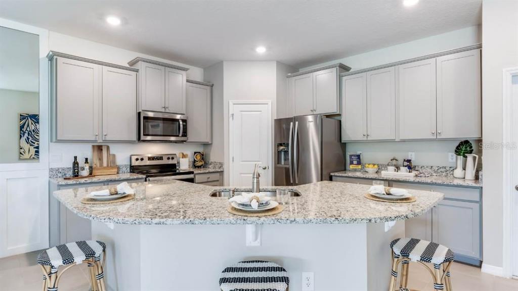 A kitchen with light gray cabinets, granite countertops, a central island, and stainless steel appliances — 316 157TH COURT E, BRADENTON, FL
