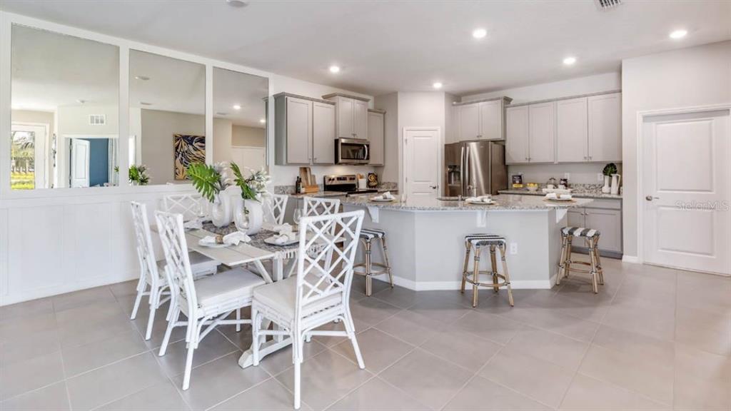 A kitchen and dining area with light gray cabinets, granite countertops, and white lattice chairs — 316 157TH COURT E, BRADENTON, FL