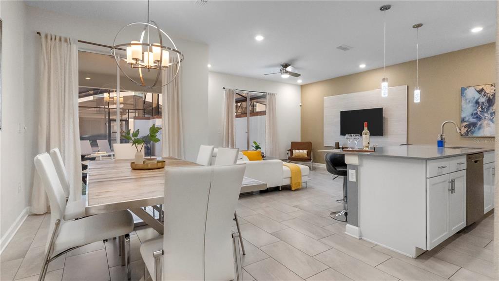 An open-concept kitchen, dining area, and living room featuring white cabinetry, tile floors, and furniture — 4804 LULLABY LANE, KISSIMMEE, FL