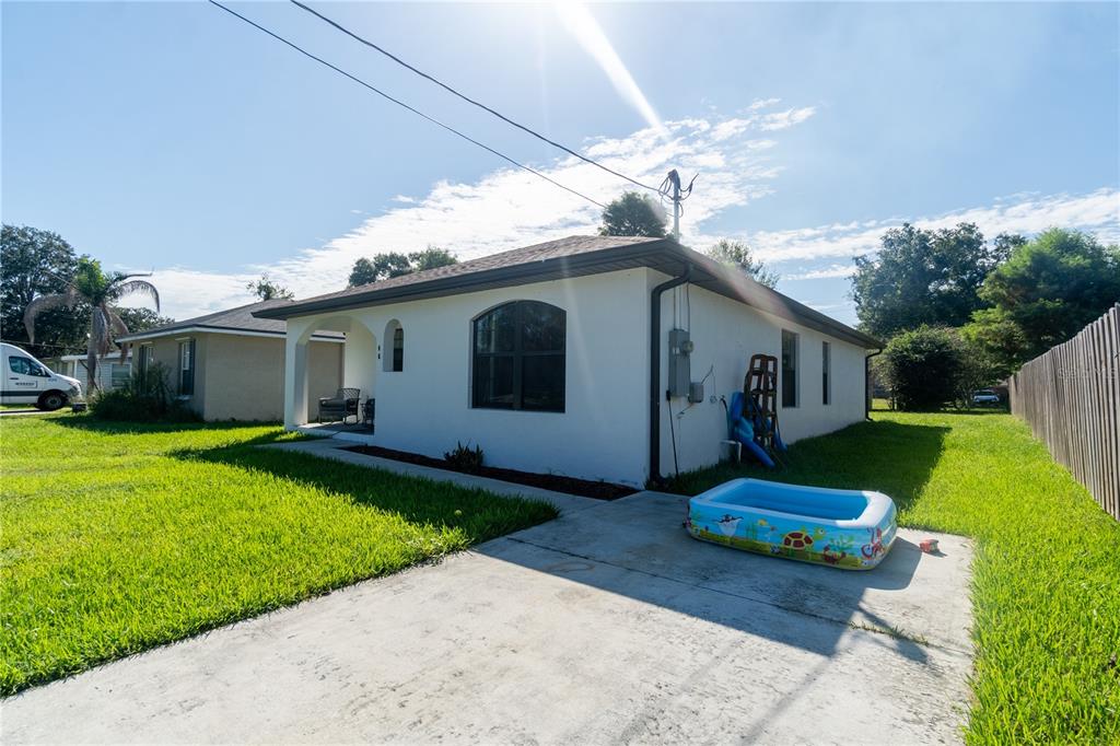 A white stucco house exterior features a small patio, a concrete driveway, and a kiddie pool — 146 8TH STREET, WINTER HAVEN, FL