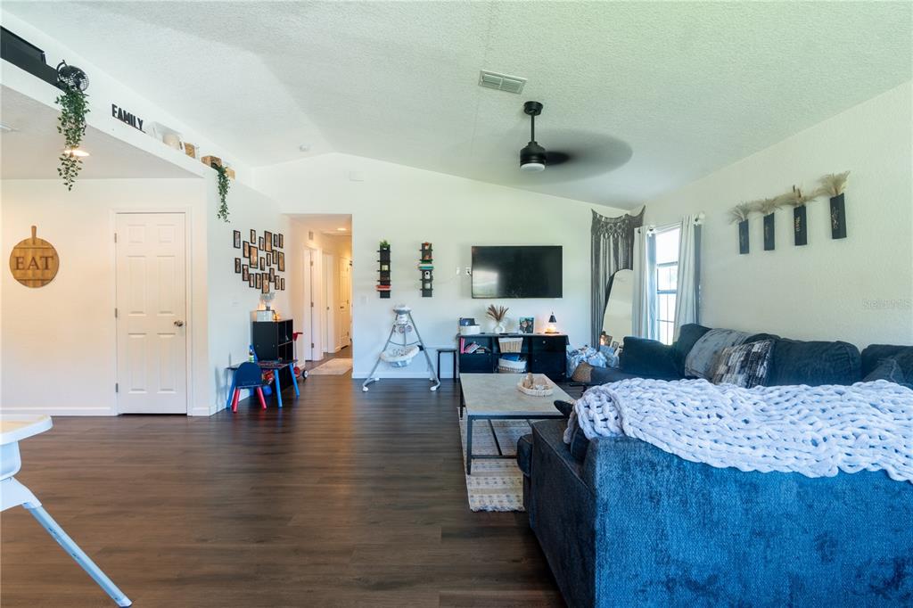 A living room features dark wood flooring, a blue sectional sofa, and a wall-mounted television — 146 8TH STREET, WINTER HAVEN, FL