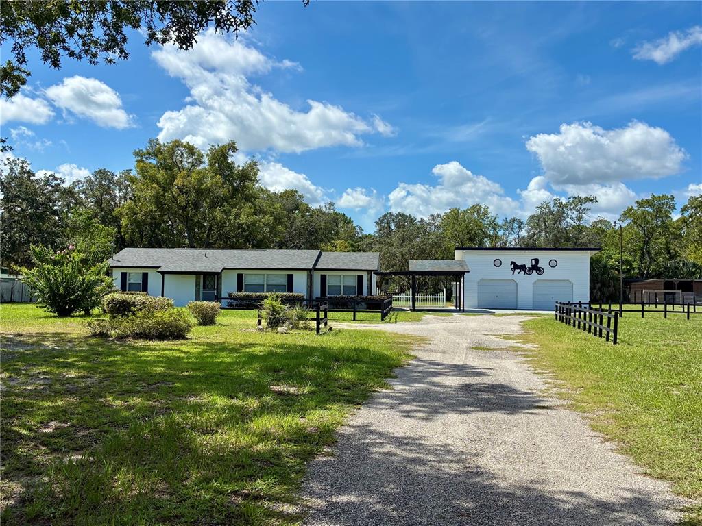 A single-story house with a white exterior, black trim, and a detached two-car garage — 17620 CHORVAT AVENUE, SPRING HILL, FL