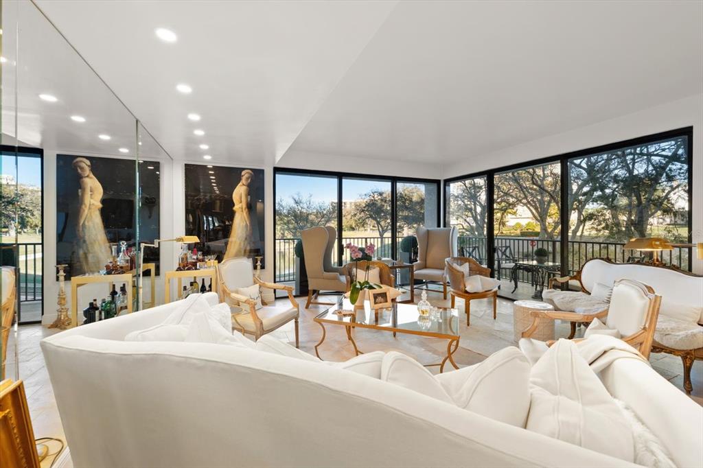 A bright living room features white furniture, a glass coffee table, and floor-to-ceiling windows — 8 BELLEVIEW BOULEVARD UNIT 203, BELLEAIR, FL