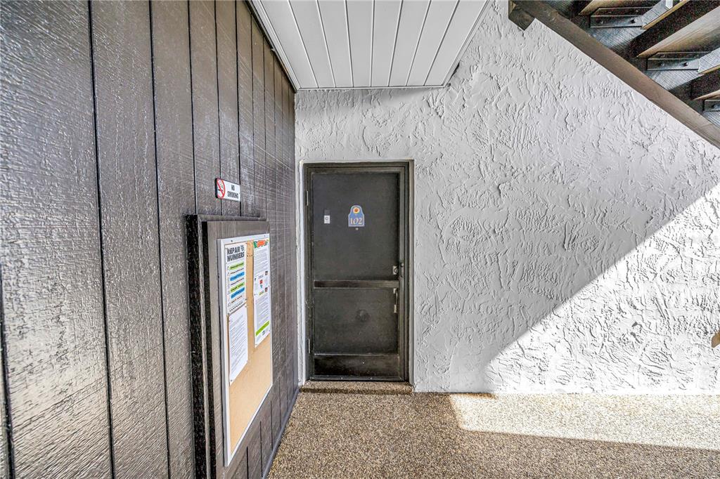 A dark door labeled 102 is set between a wood-paneled wall and a textured white wall — 3269 BENEVA ROAD UNIT 102, SARASOTA, FL
