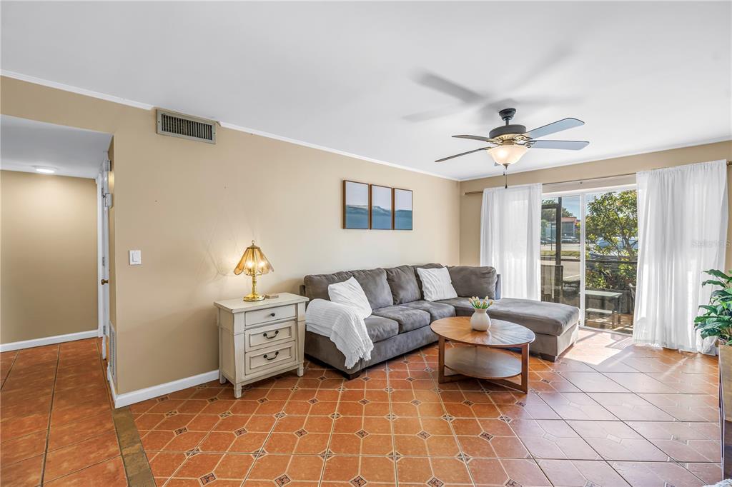 A living room features a grey sectional sofa, a round wooden coffee table, and tile flooring — 3269 BENEVA ROAD UNIT 102, SARASOTA, FL