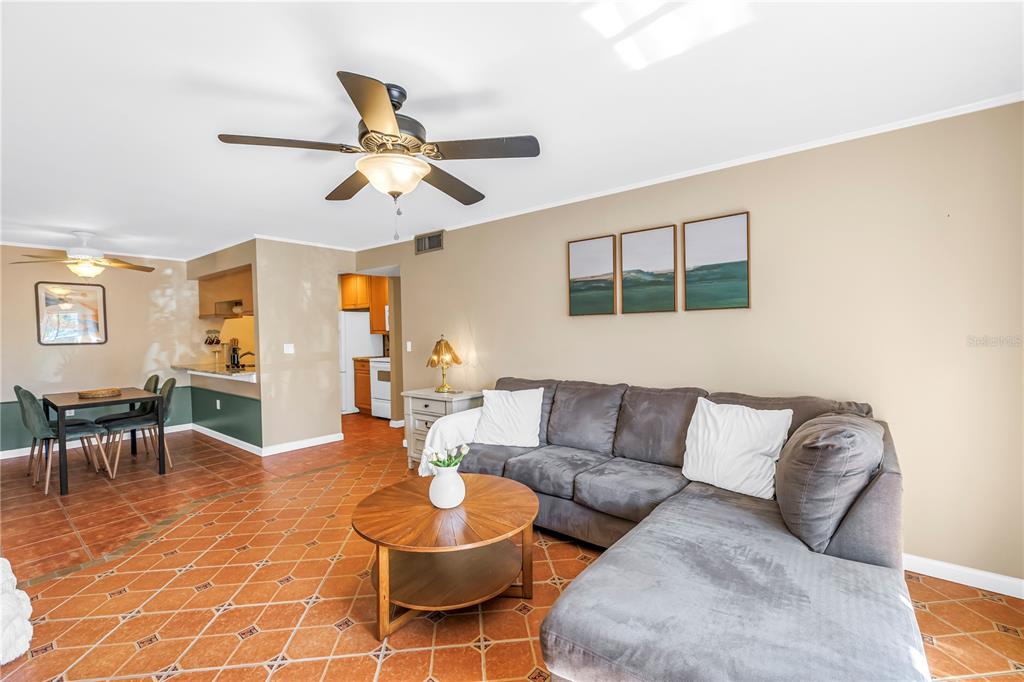 A living room with a gray sectional sofa, a round wooden table, and tiled floors — 3269 BENEVA ROAD UNIT 102, SARASOTA, FL