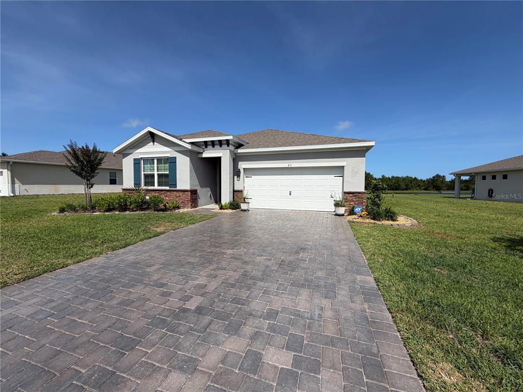 A covered patio overlooks a grassy lawn, a small pond, and a wooded area — 85 HUNTINGTON PLACE, ORMOND BEACH, FL