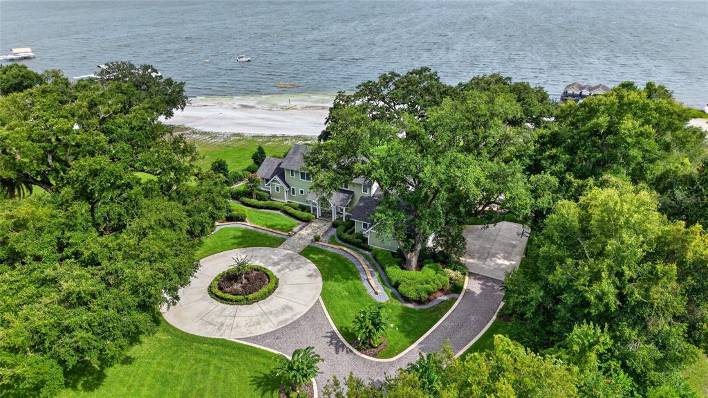 An aerial view shows a green house with a circular driveway surrounded by lush trees — 12950 E HIGHWAY 25, OCKLAWAHA, FL
