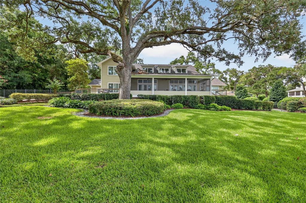 A large oak tree stands in the front yard of a two-story house with a porch — 12950 E HIGHWAY 25, OCKLAWAHA, FL