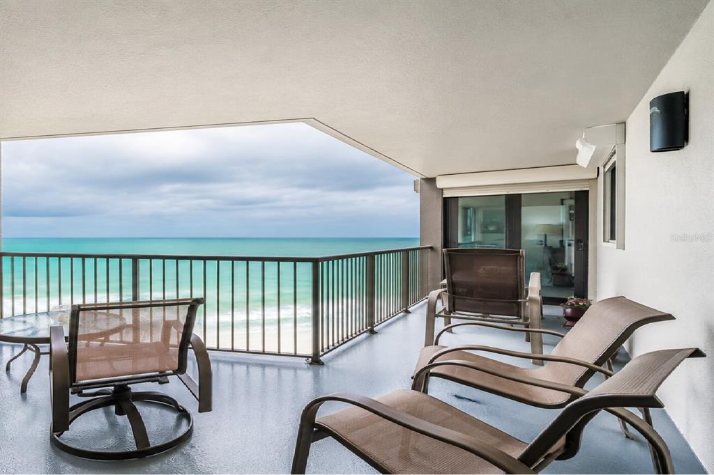 A balcony with patio furniture overlooks the ocean under a cloudy sky — 1600 GULF BOULEVARD UNIT 1013, CLEARWATER, FL