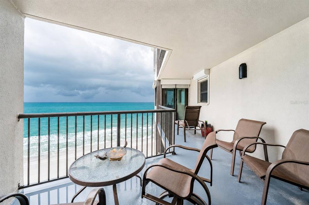 A balcony with outdoor furniture overlooks the ocean under a cloudy sky — 1600 GULF BOULEVARD UNIT 1013, CLEARWATER, FL