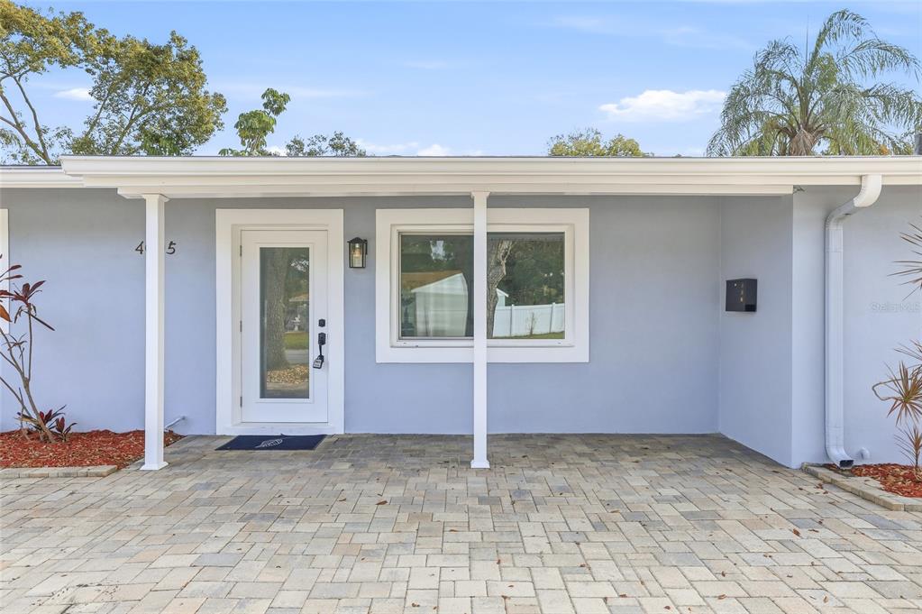 The exterior of a light blue house features a paver patio and a white door — 4095 LOCUST STREET NE, ST PETERSBURG, FL
