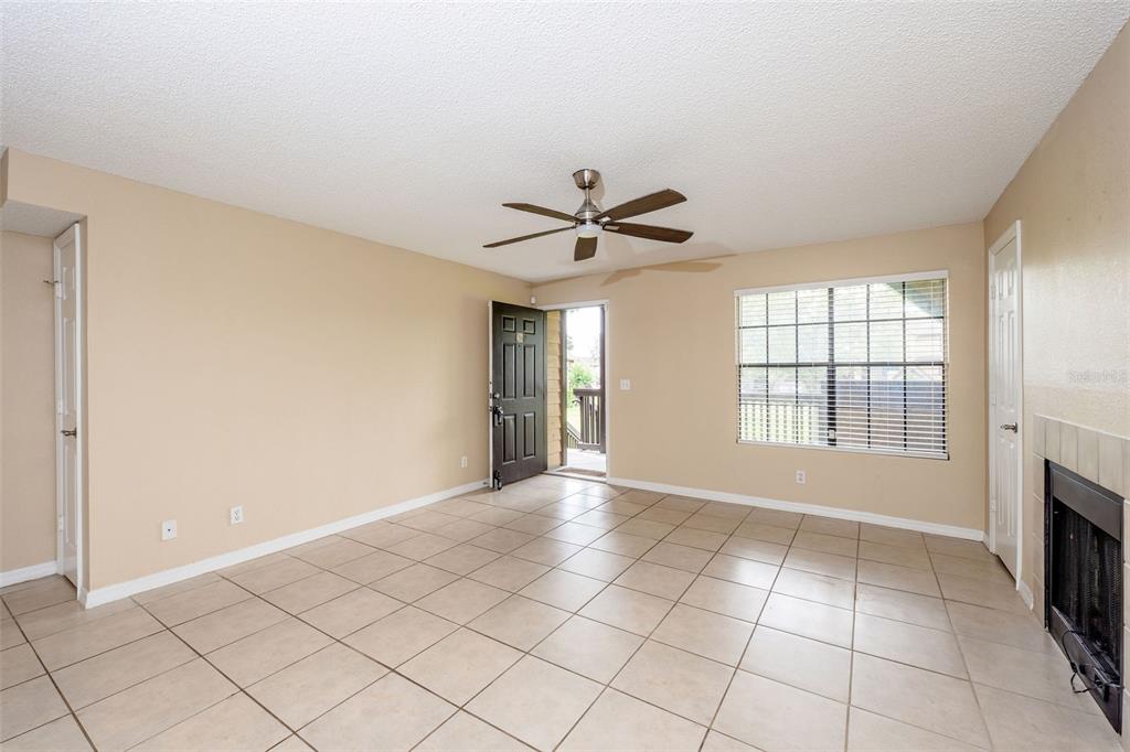 A living room with beige walls, tile flooring, a ceiling fan, and a fireplace — 420 FORESTWAY CIRCLE UNIT 206, ALTAMONTE SPRINGS, FL