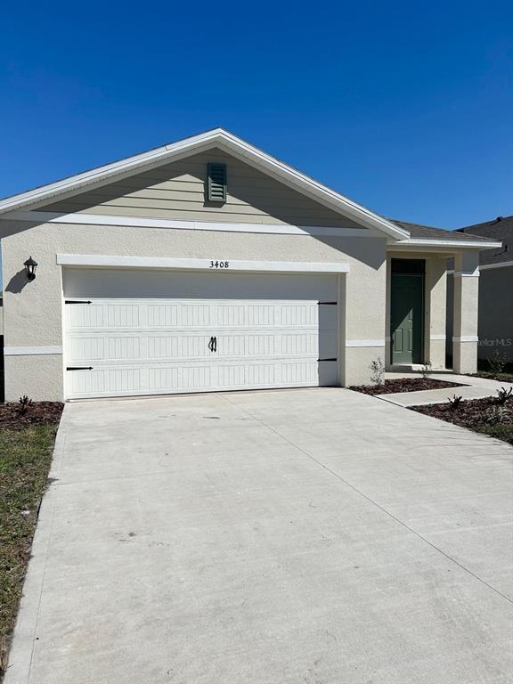 A single-story house with a beige stucco exterior, a two-car garage, and a green door — 3408 COSTELLO CIRCLE, WINTER HAVEN, FL