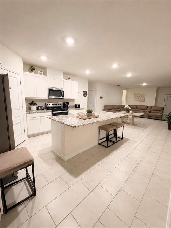A kitchen with white cabinets, granite countertops, and an island opens to a living area — 3408 COSTELLO CIRCLE, WINTER HAVEN, FL