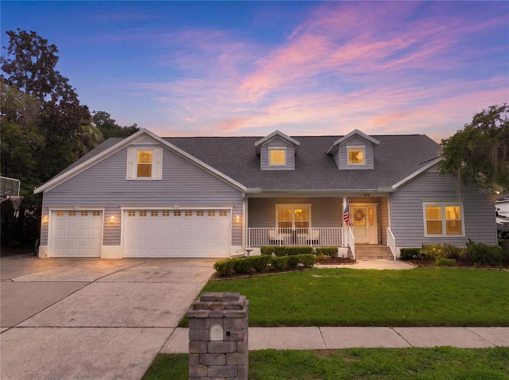 A light blue house with a three-car garage, front porch, and two roof dormers — 504 COVINGTON PARK STREET, SEFFNER, FL