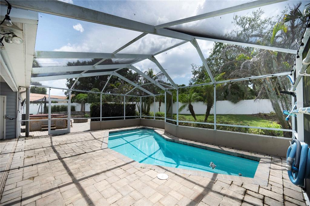 A screened-in patio features a rectangular swimming pool, paver flooring, and a hot tub — 504 COVINGTON PARK STREET, SEFFNER, FL
