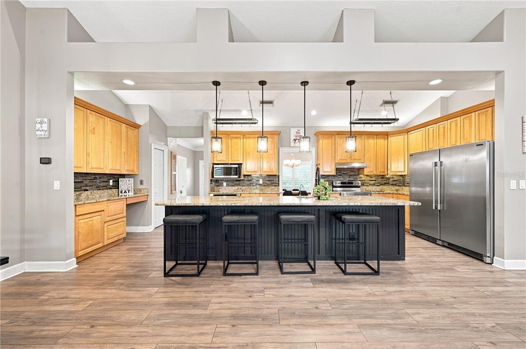 A kitchen features light wood cabinets, a dark island with four stools, and stainless appliances — 504 COVINGTON PARK STREET, SEFFNER, FL