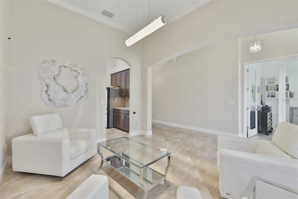 A living room features white leather armchairs, a glass coffee table, and tile flooring — 7121 HATPIN LOOP, WESLEY CHAPEL, FL