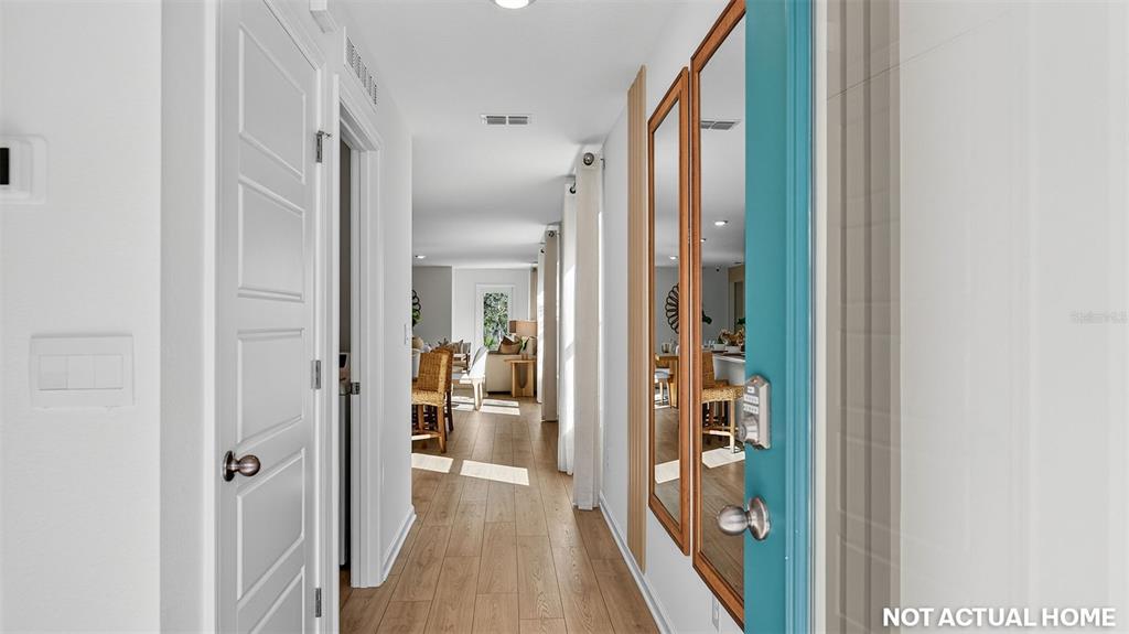 A hallway with light wood flooring leads to an open living area — 16 FLAGSTICK LANE, BUNNELL, FL