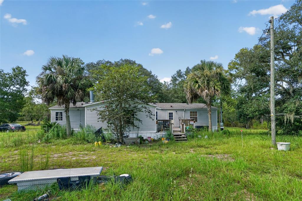 A single-story manufactured home sits on a grassy lot with palm trees and a utility pole — 8351 NE 106TH STREET, BRONSON, FL