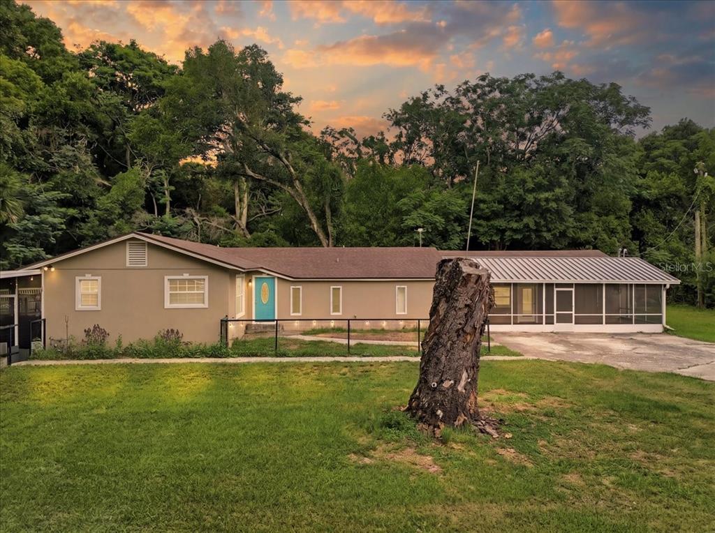 A single-story house with a turquoise front door and a screened-in porch at sunset — 8095 ROSE AVENUE, ORLANDO, FL