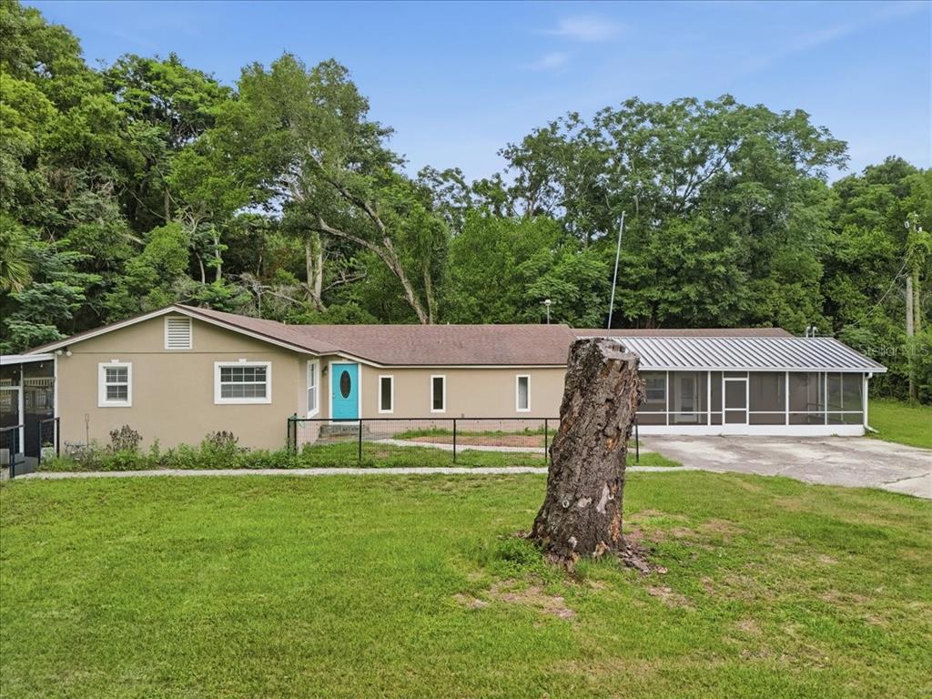 A single-story house with a tan exterior, a bright blue front door, and a screened porch — 8095 ROSE AVENUE, ORLANDO, FL
