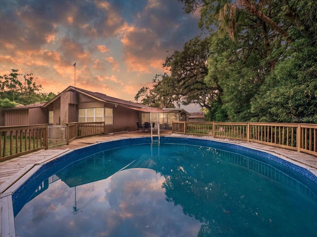 An above-ground swimming pool with a wooden deck sits in the backyard of a house — 8095 ROSE AVENUE, ORLANDO, FL