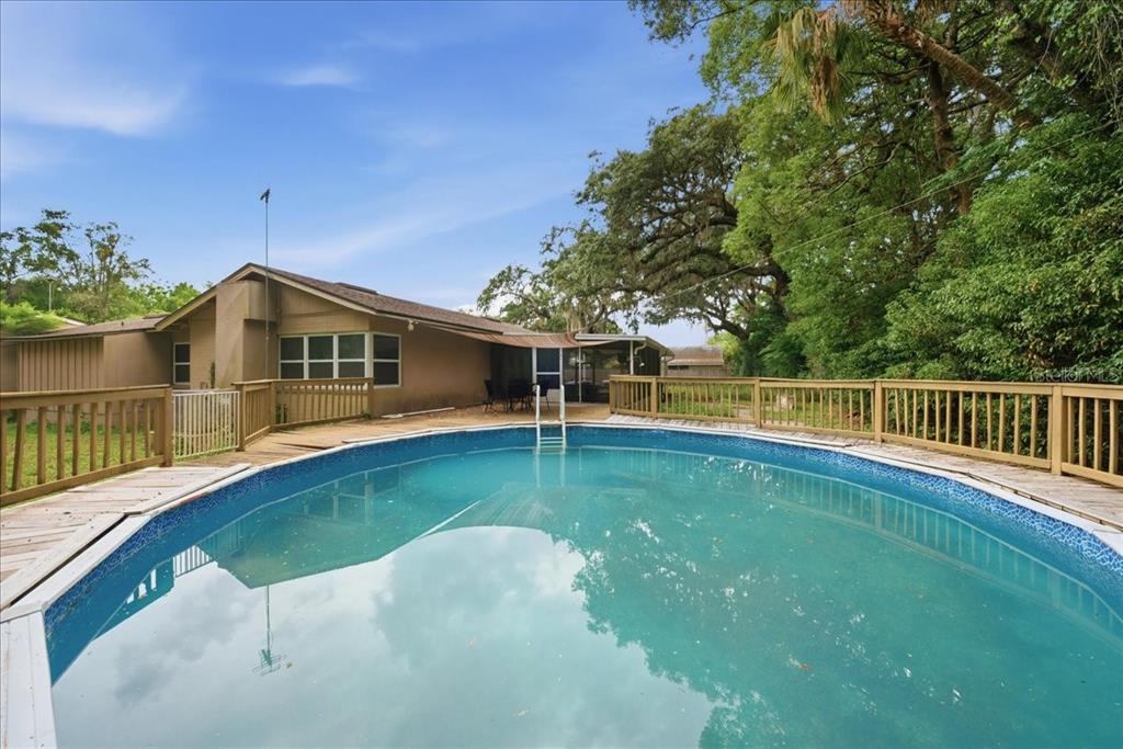 An above-ground swimming pool sits on a wooden deck behind a single-story house — 8095 ROSE AVENUE, ORLANDO, FL